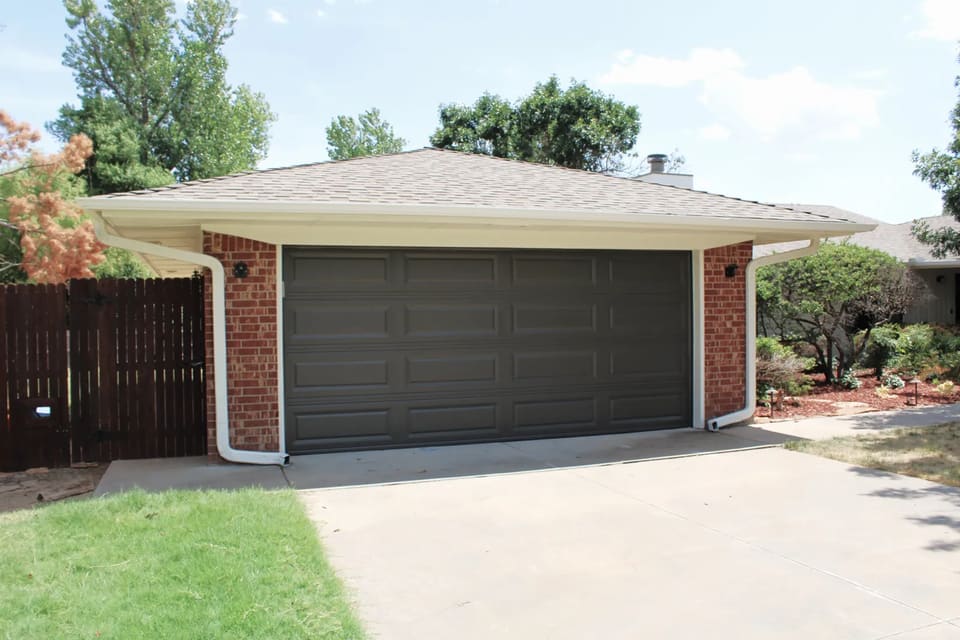 Garage door painted dark bronze on a brick home in Bethany, OK