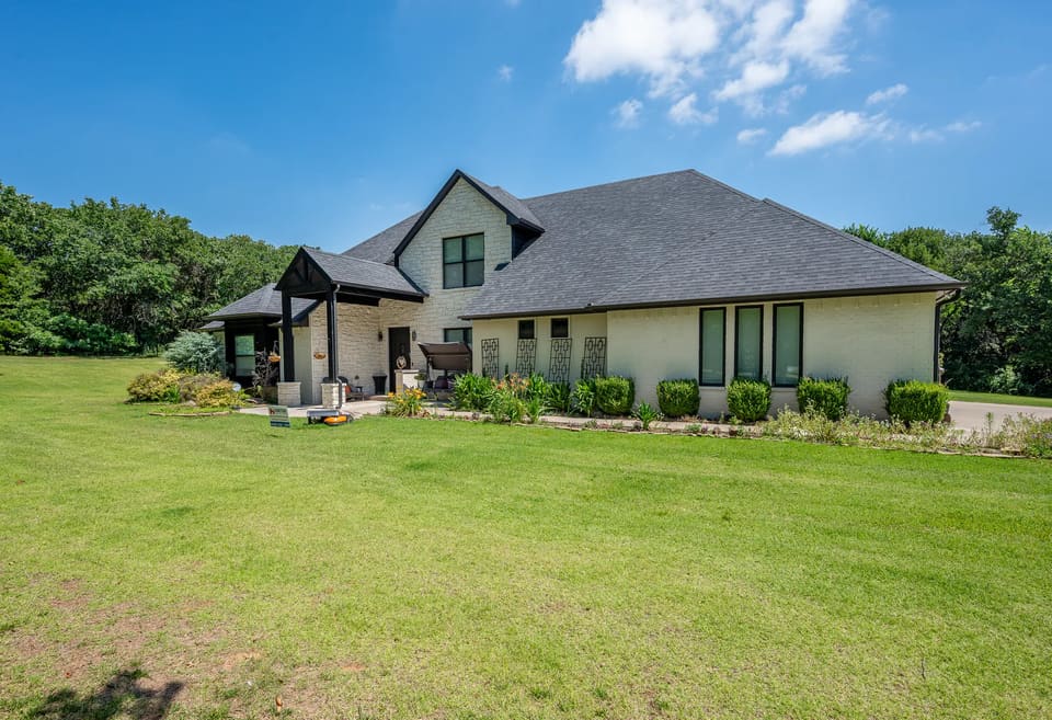 After: side view of the same Edmond home with solid off-white painted masonry and black accents