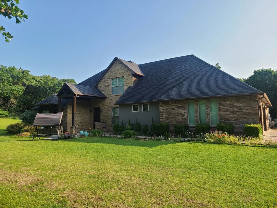 Before: side view of the tan stone and brick home in Edmond prior to painting