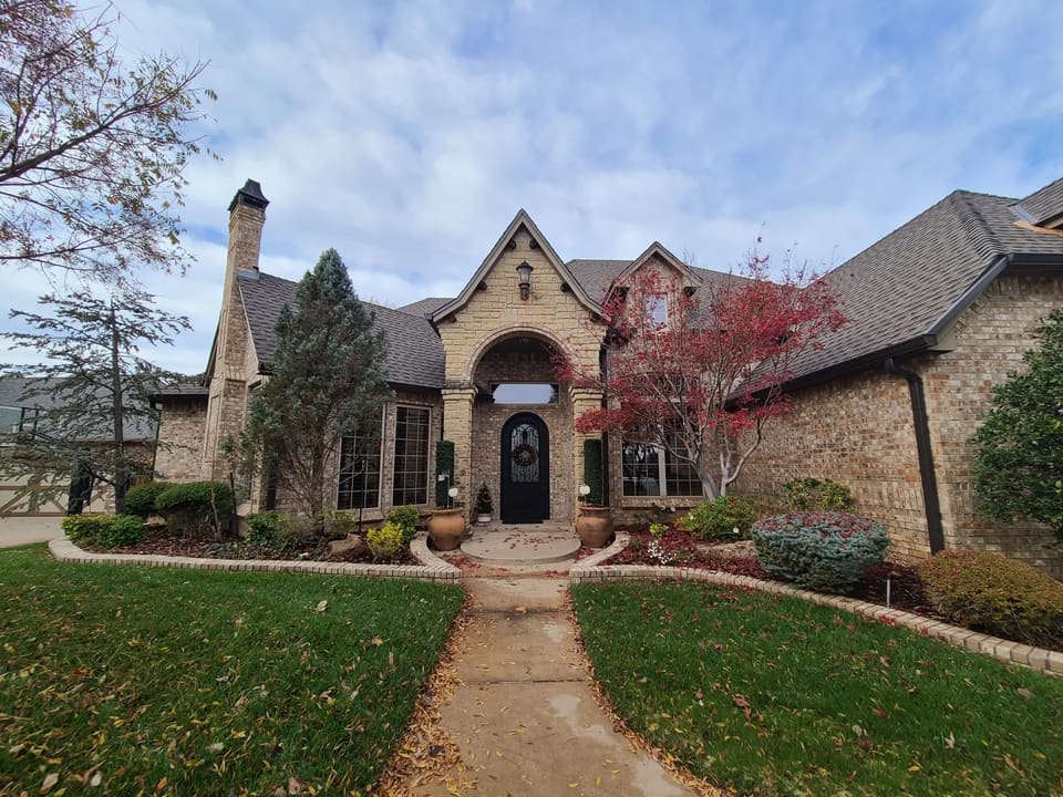 Stone and brick Edmond home with an arched entry and painted front door