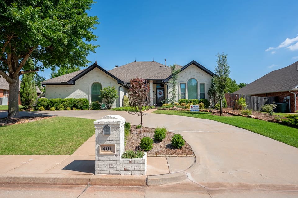 Edmond home with a cream limewash brick finish, black eaves, and arched windows
