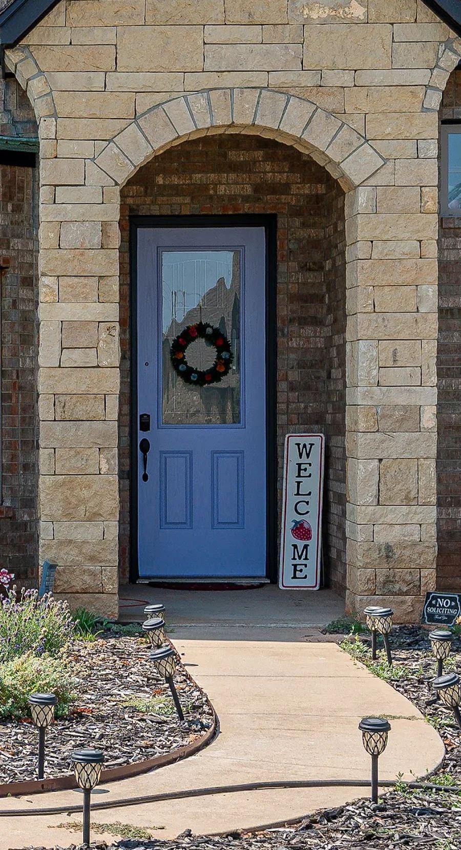 Close-up of the Awesome Violet front door with black hardware under the stone archway of a Yukon, OK brick home