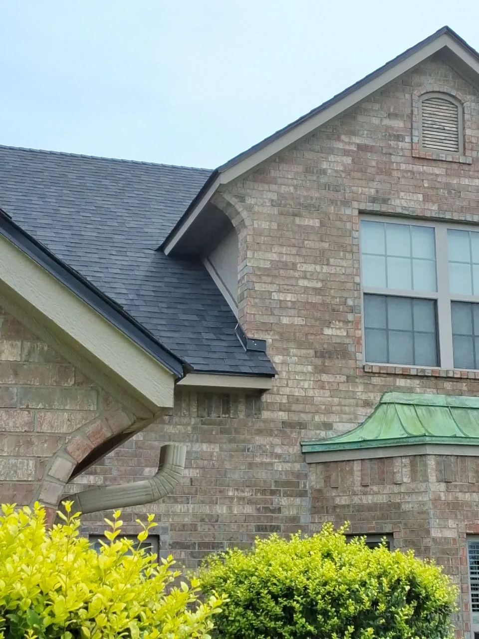 Before: close view of the new dark shingles meeting the Yukon home's unpainted cream fascia and soffits