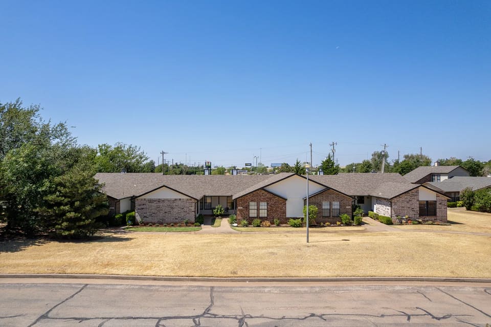Single-story townhome row at The Crossing in Edmond, OK after exterior painting, with bright white gables over brick